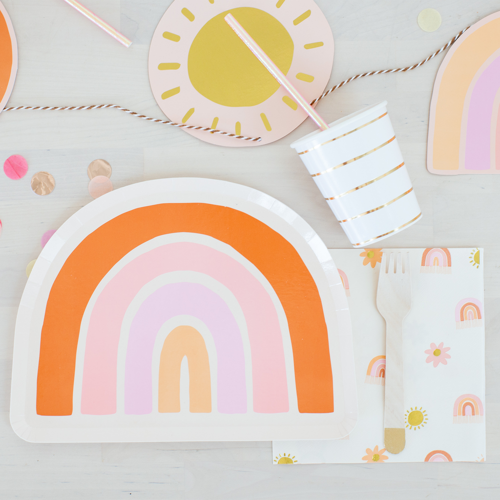 Colorful rainbow-themed plates, cups, and napkins on a light gray background