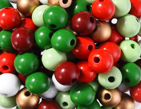 A pile of glossy round wooden beads in red, green, light green, white, and metallic gold, each with a hole through the center, photographed on a white background.
